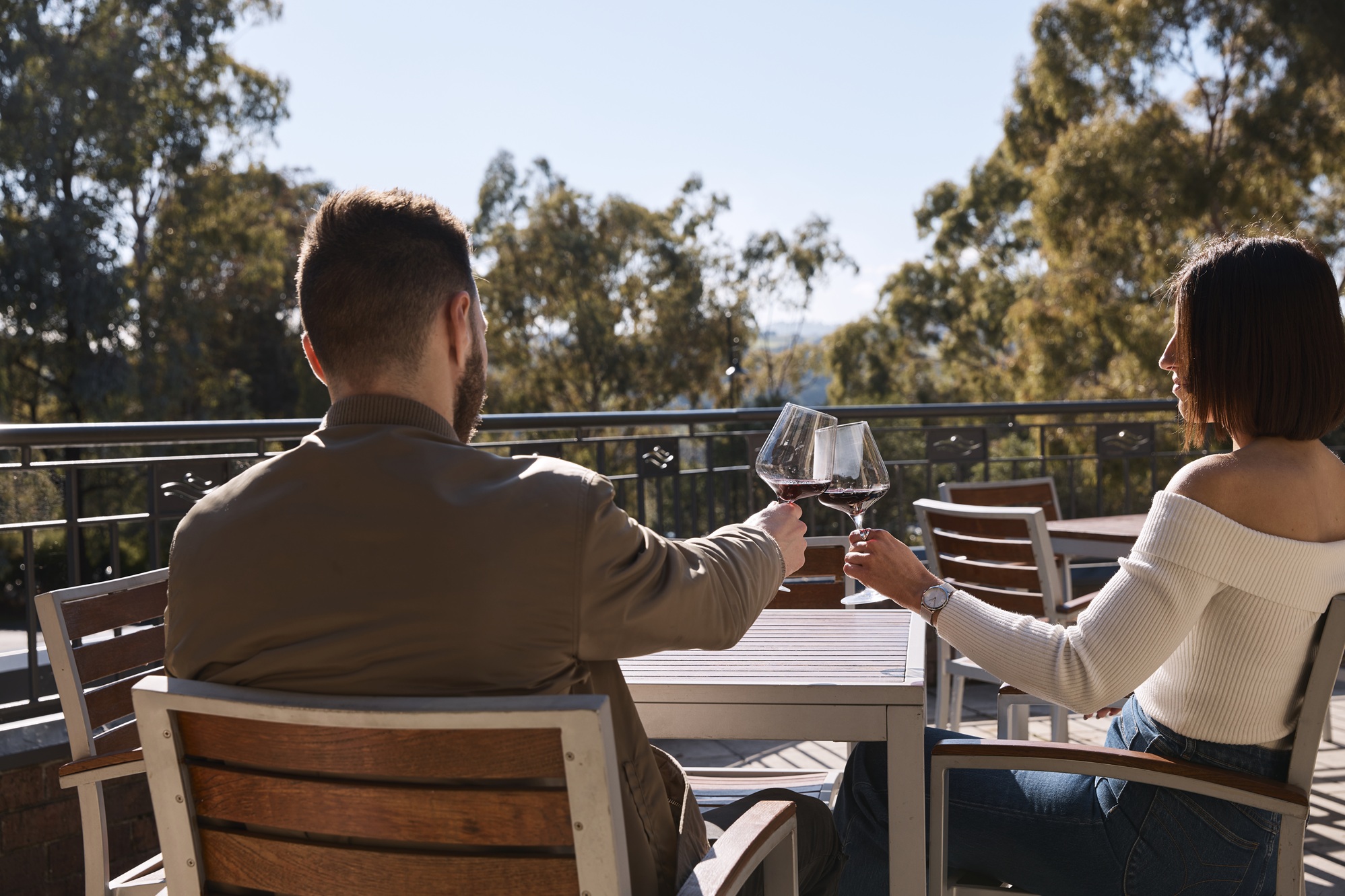 Guest cheersing wine on balcony at Yarra Valley Lodge
